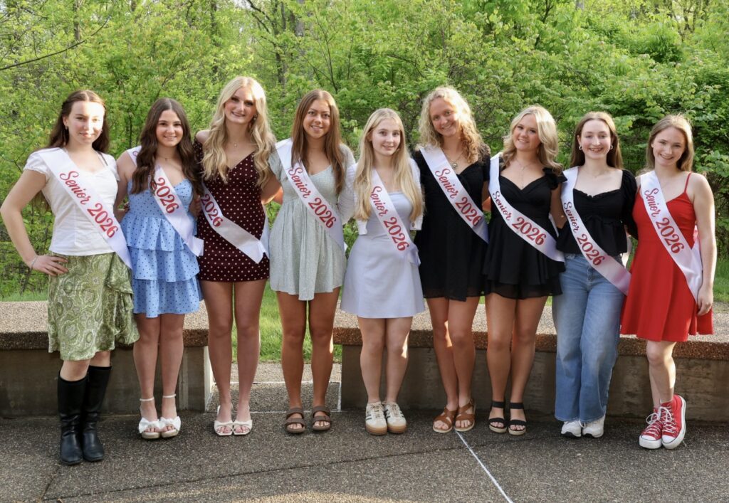 A group of girls wearing dresses and sashes that say "Senior 2026" standing outside